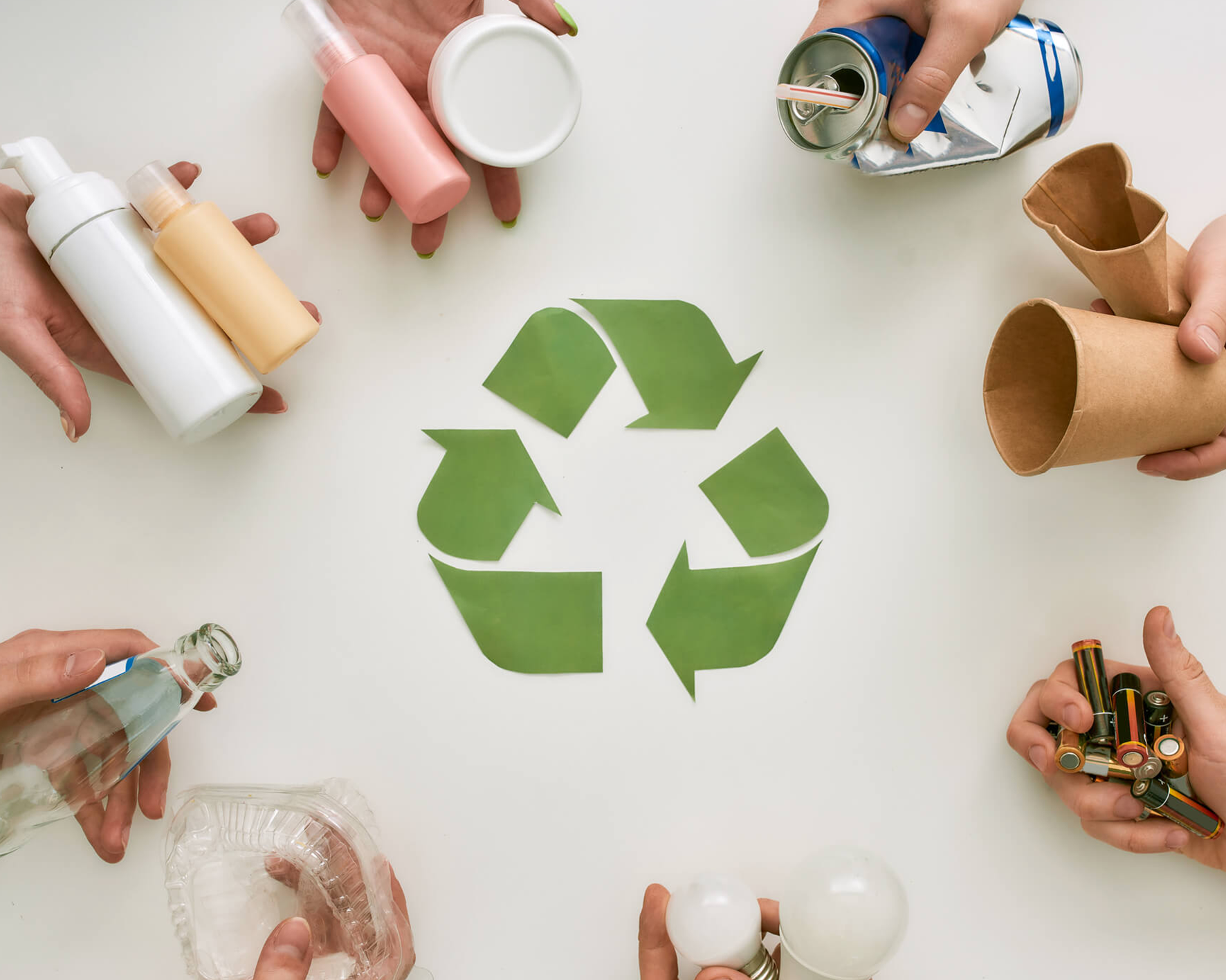 Image of 8 hands holding a item thats goes
    into the recycling bin with a recyling logo in the centre of them